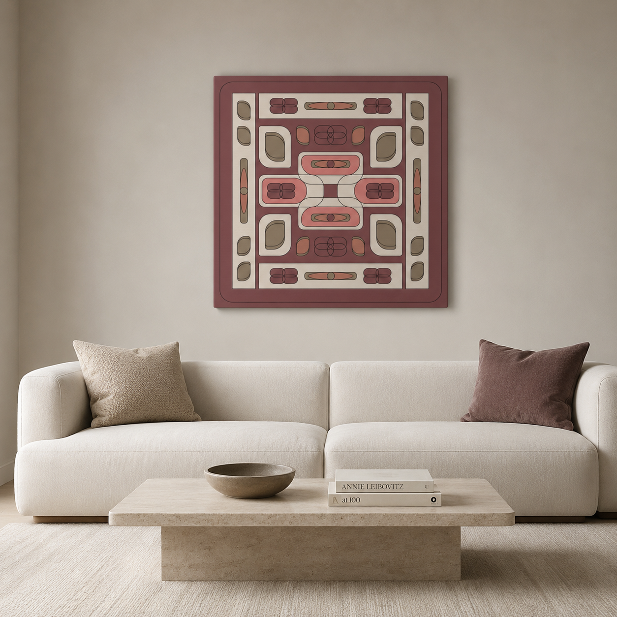 A square abstract wall art print with a muted burgundy border and cream, dusty pink, and olive geometric pattern, displayed above a modern white sofa in a minimalist living room setting.