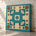 A square canvas print featuring a mid-century modern geometric pattern in teal, cream, beige, and rust orange, leaning against a white brick wall on a stone floor.