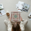 Geometric pink mauve canvas print held by dark-haired woman, overhead view with magazines and tea, 16x16